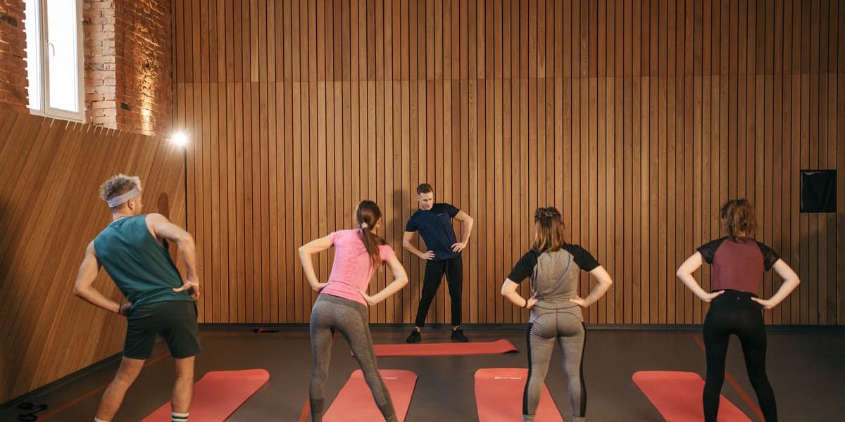 People stretching on yoga mats during a fitness class indoors.