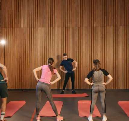 People stretching on yoga mats during a fitness class indoors.